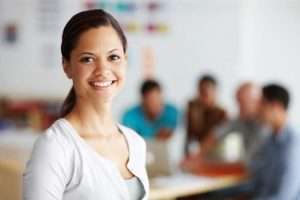 Portrait of a positive-looking young professional with her colleagues working in the background